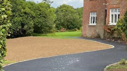 A brick house with a gravel driveway leading to it.