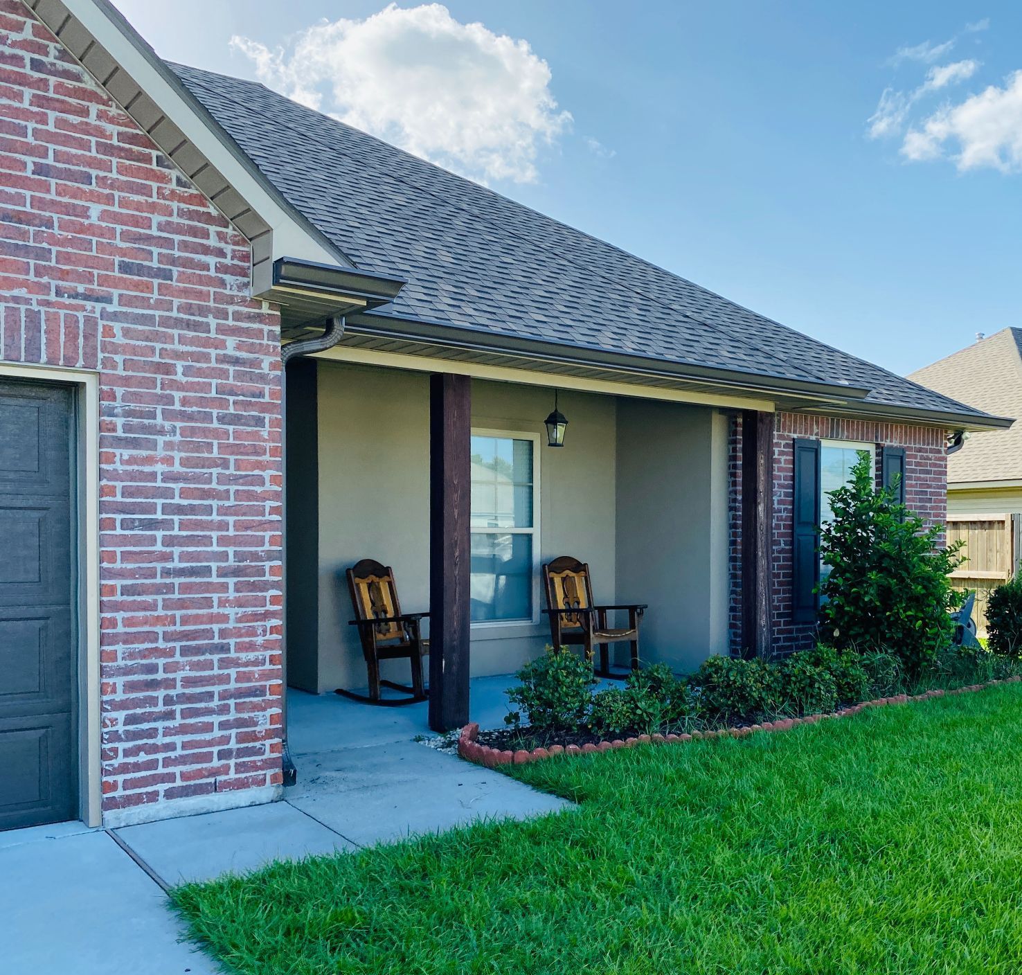 A brick house with a porch and rocking chairs