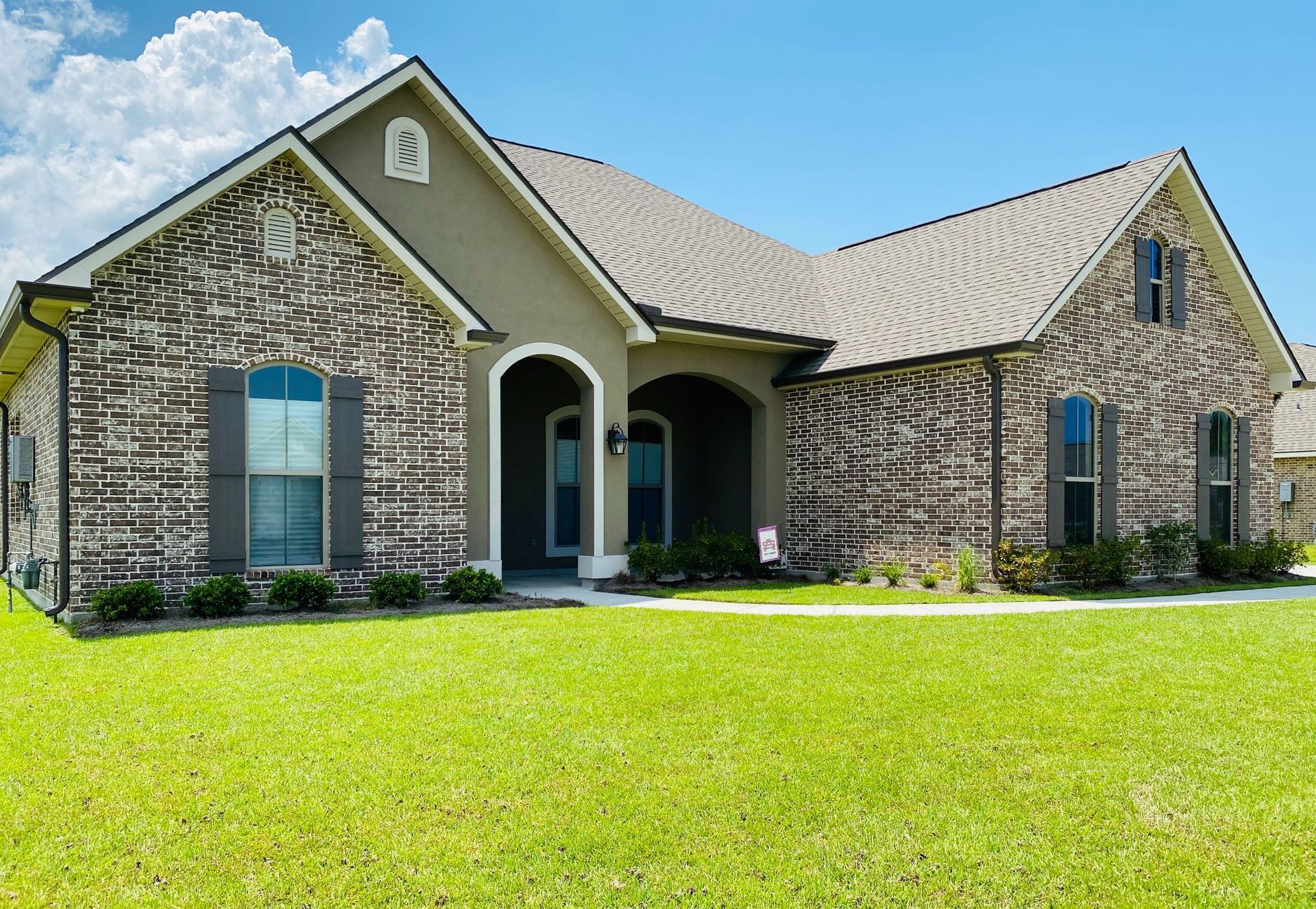 A large brick house with a lush green lawn in front of it.