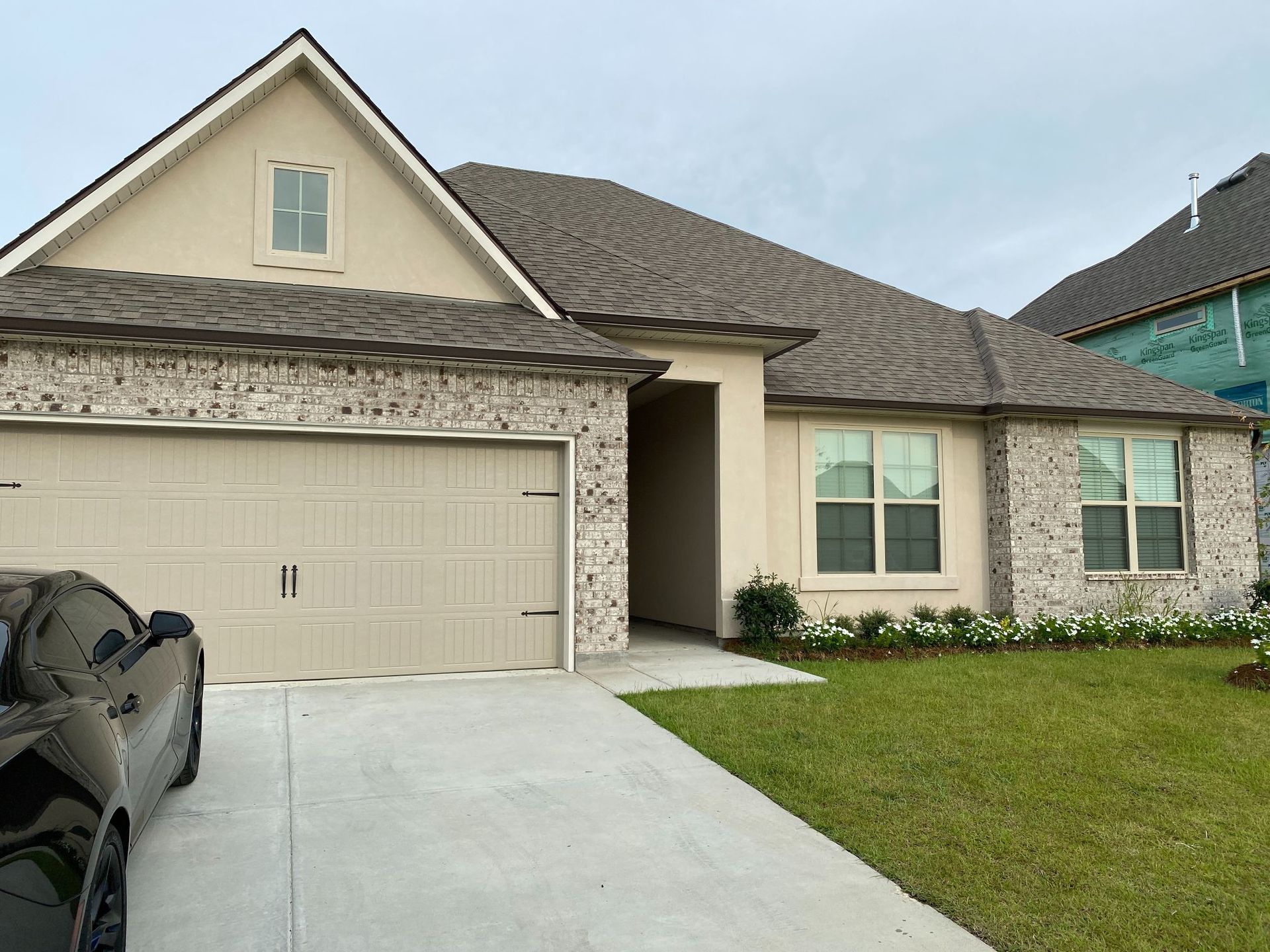 A car is parked in front of a house with a garage.
