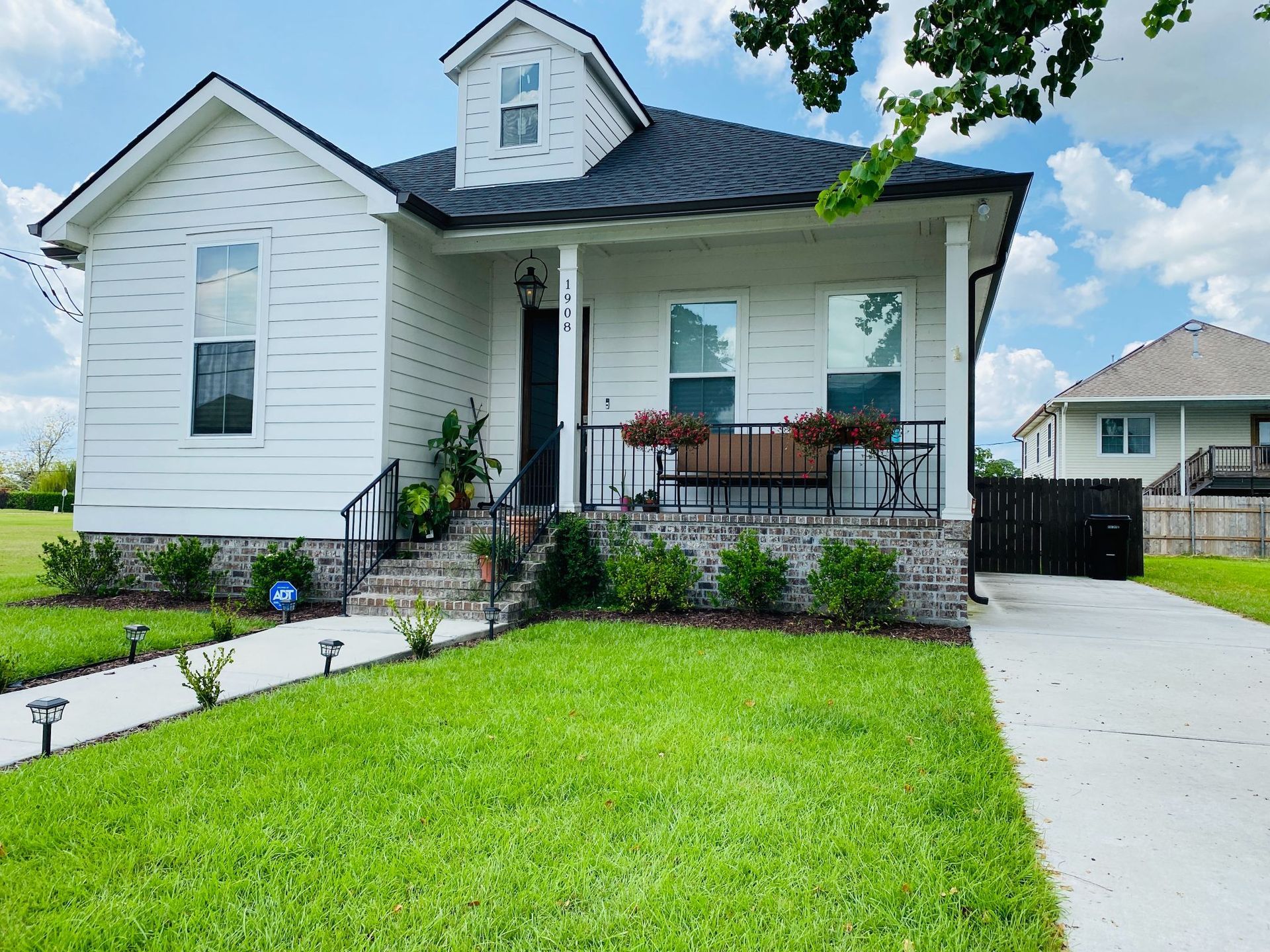 A white house with a black roof is sitting on top of a lush green lawn.
