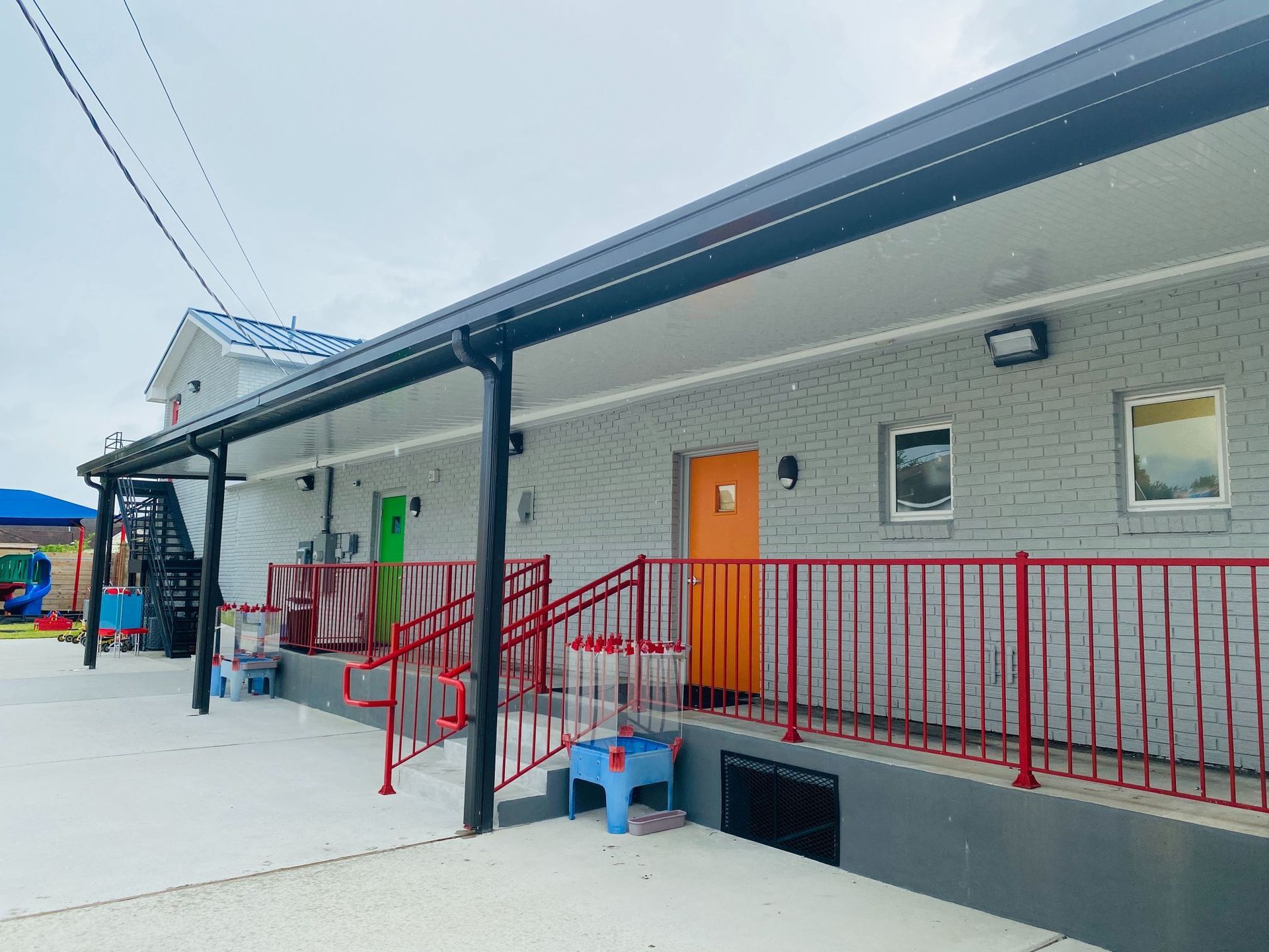 A large brick building with a red railing and stairs leading up to it.