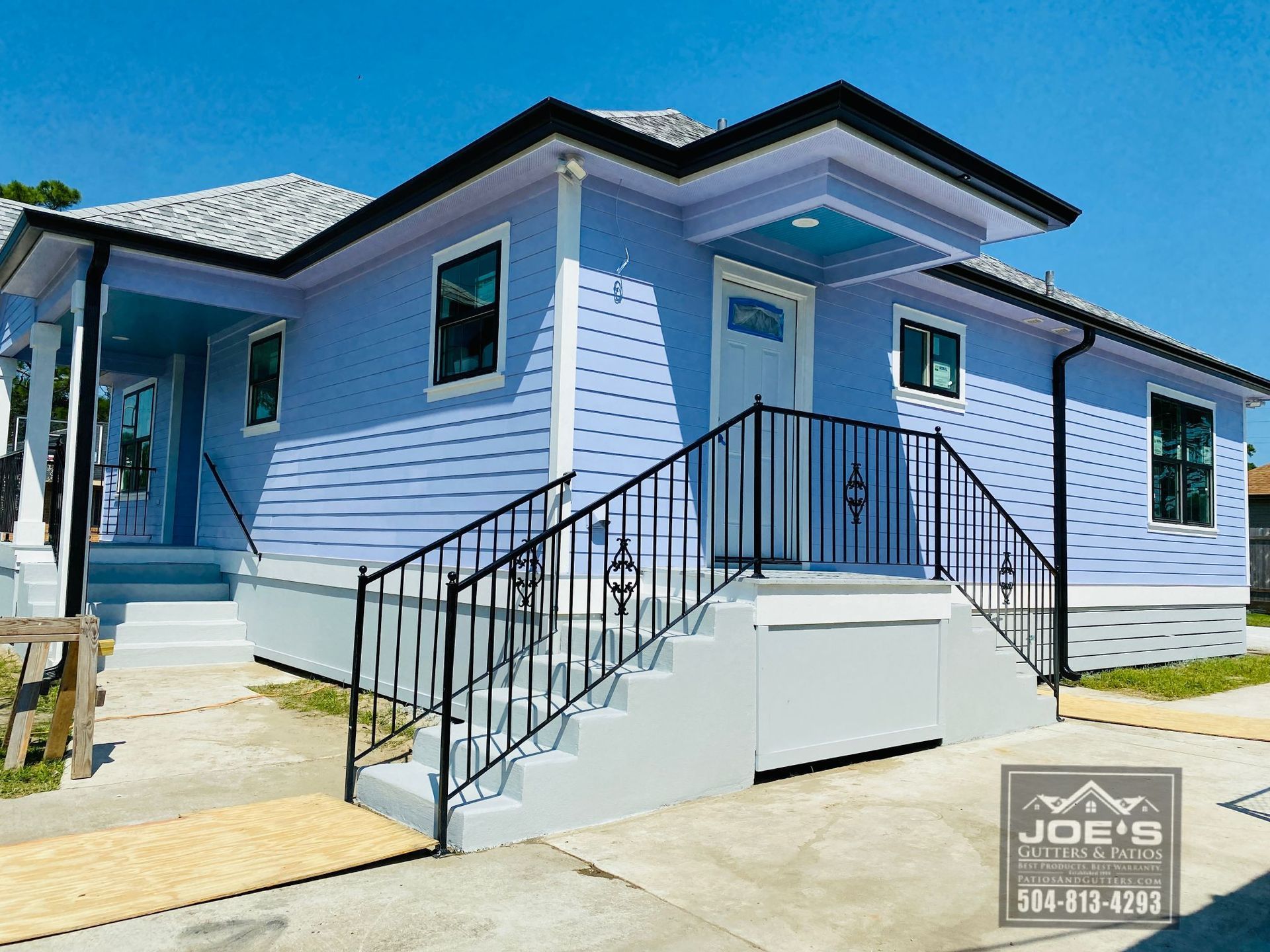 A purple and white house with stairs and a wrought iron railing
