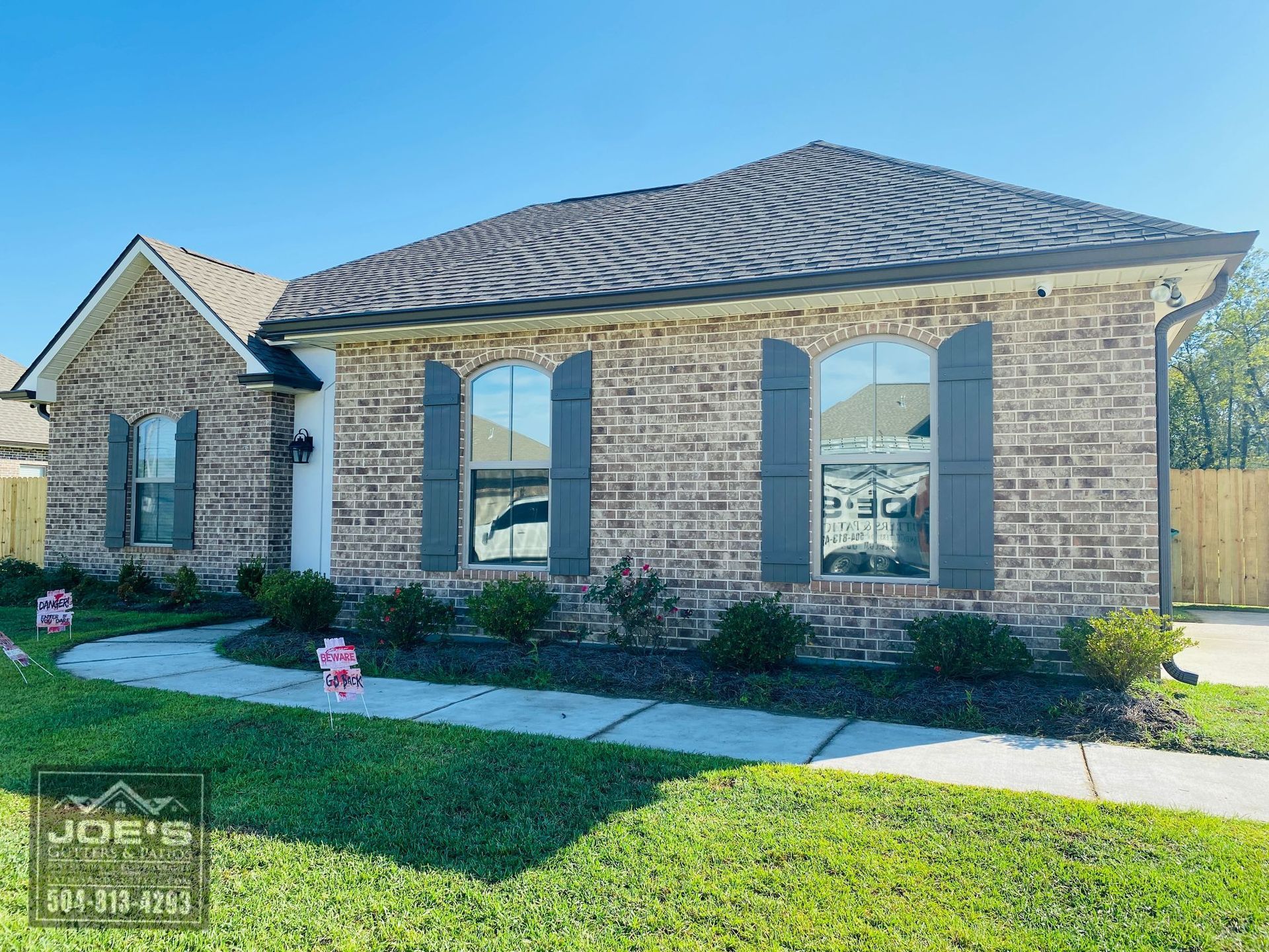 A brick house with a roof and shutters on the windows