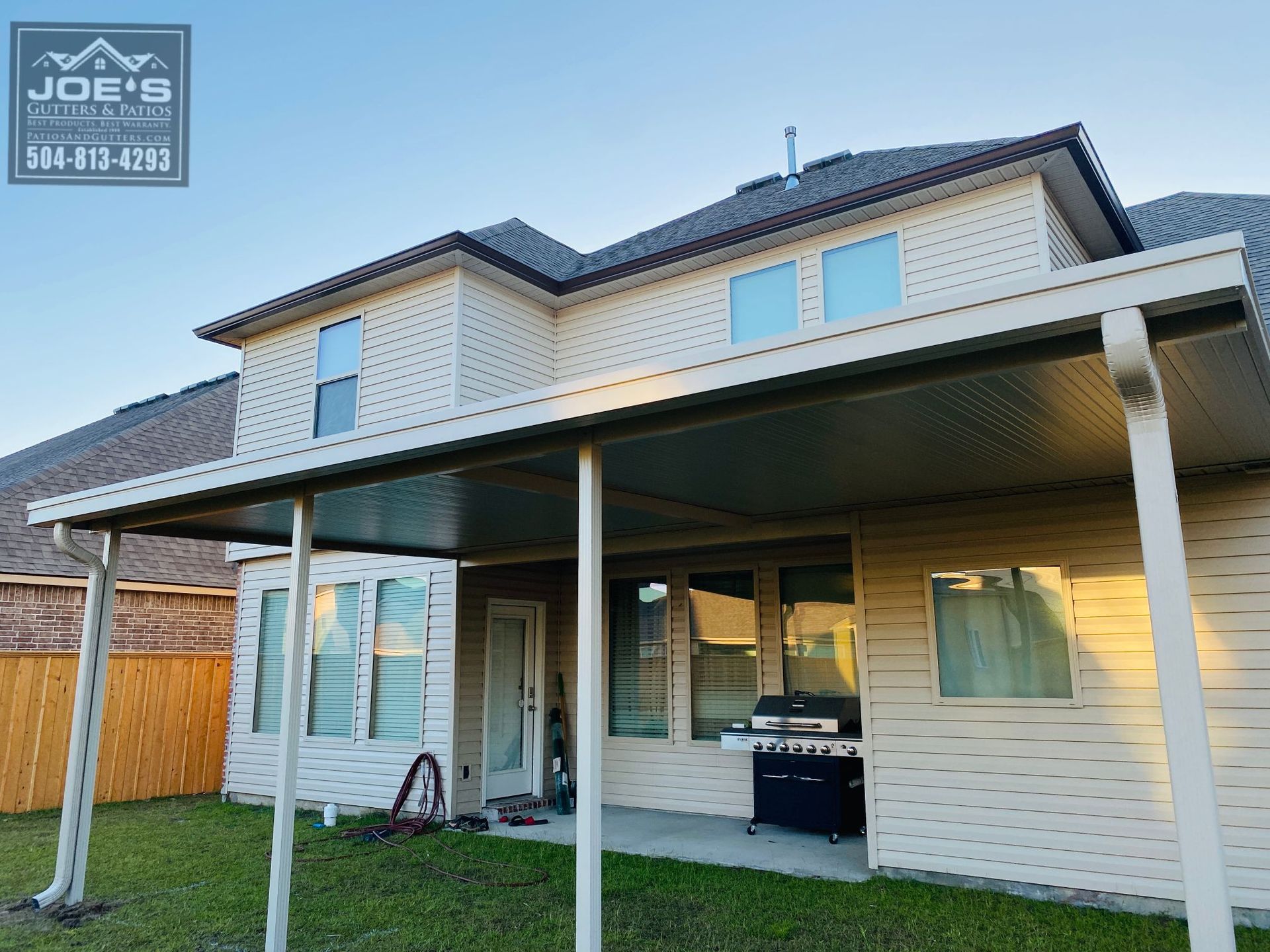 A house with a covered patio and a grill in the backyard.