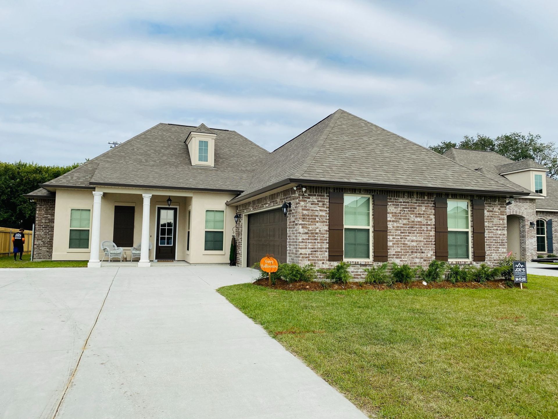 A large brick house with a large driveway and a pumpkin in front of it.