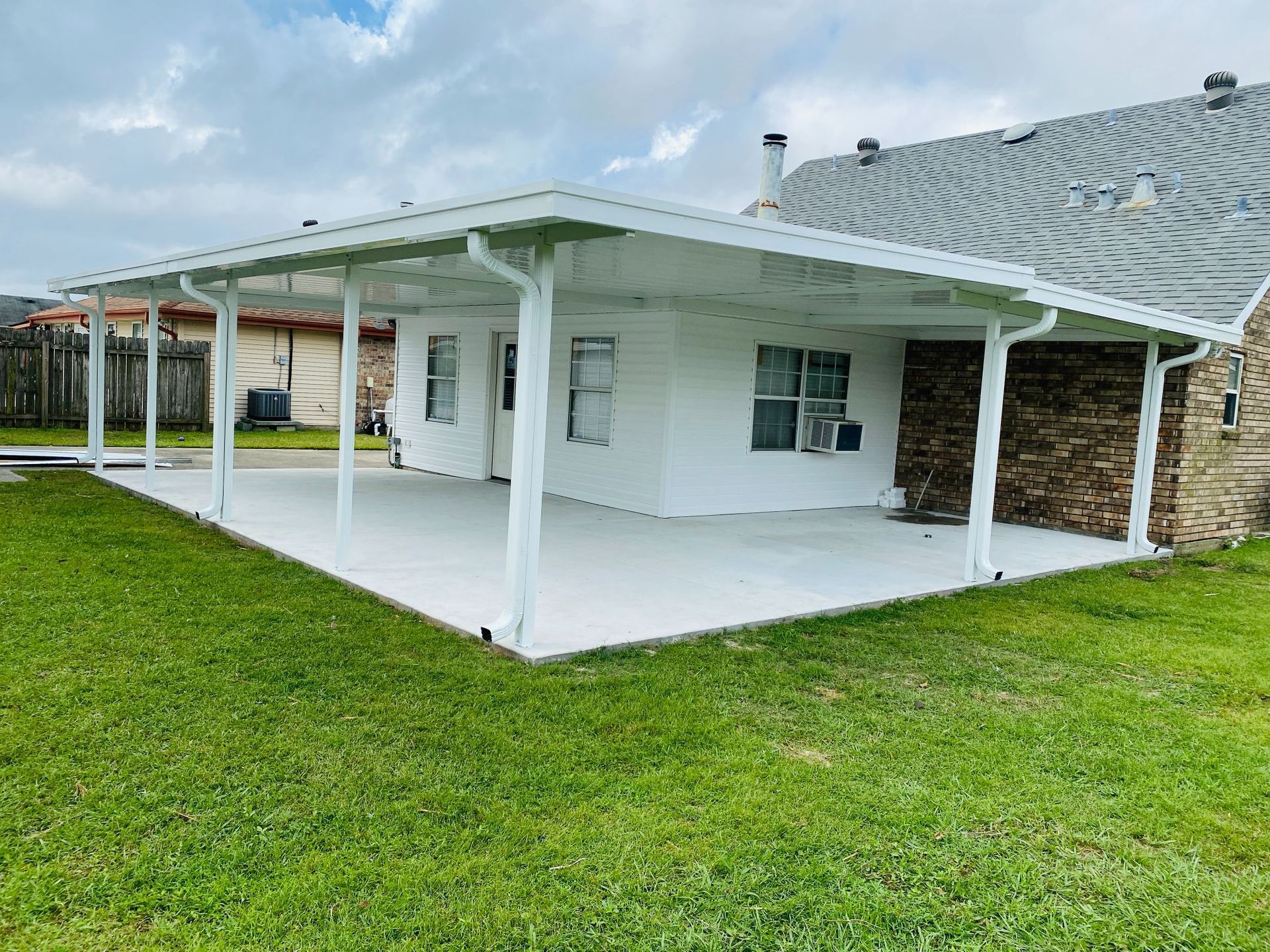 A white house with a covered patio in front of it.