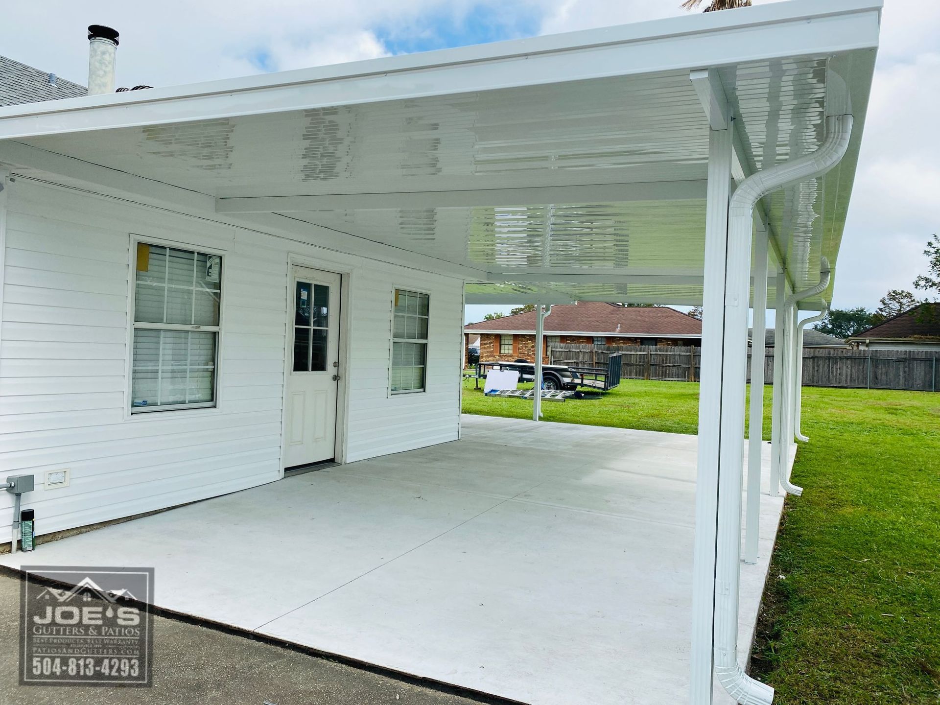 A white house with a covered patio in front of it.
