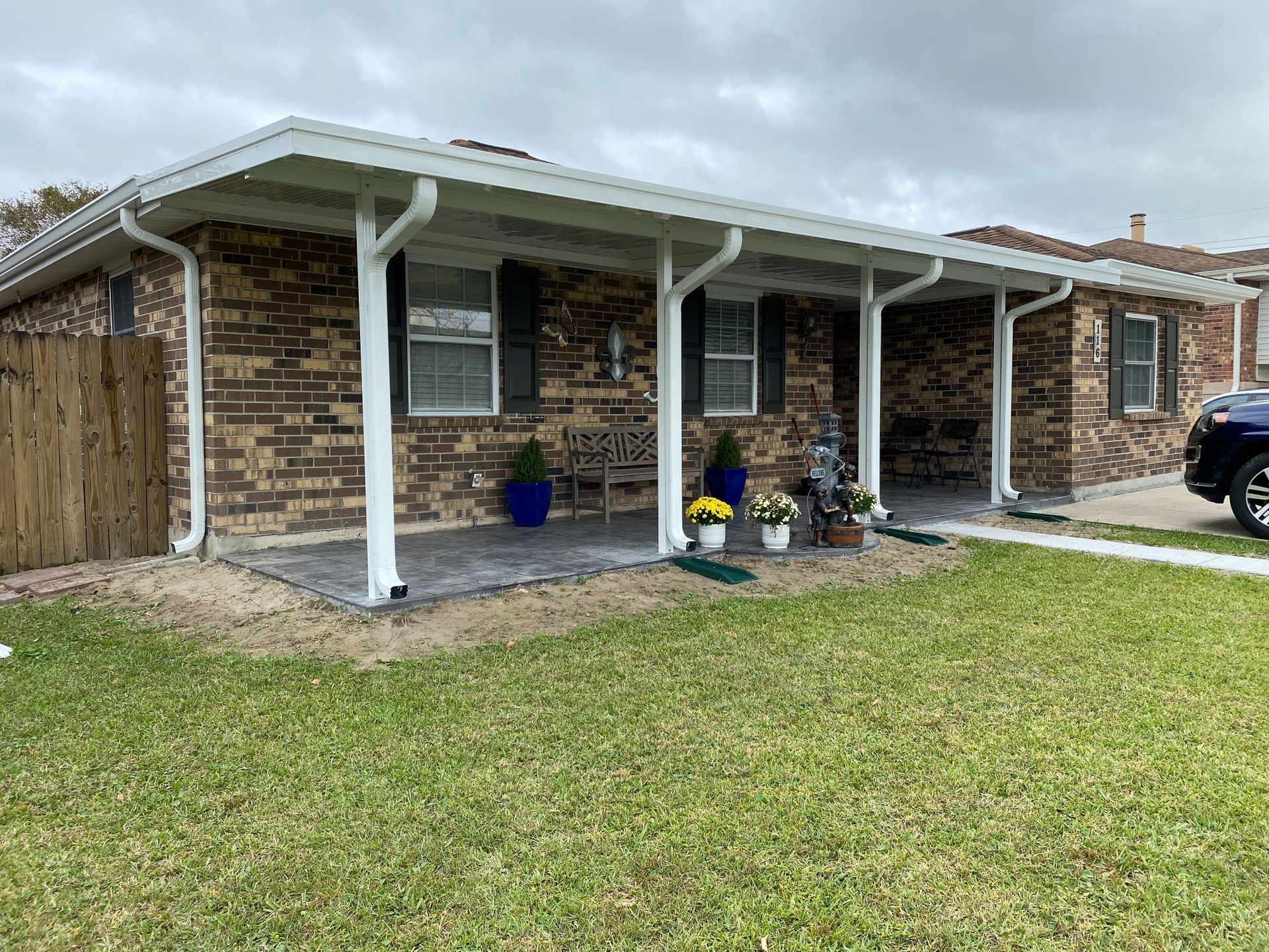 A brick house with a porch and a car parked in front of it.