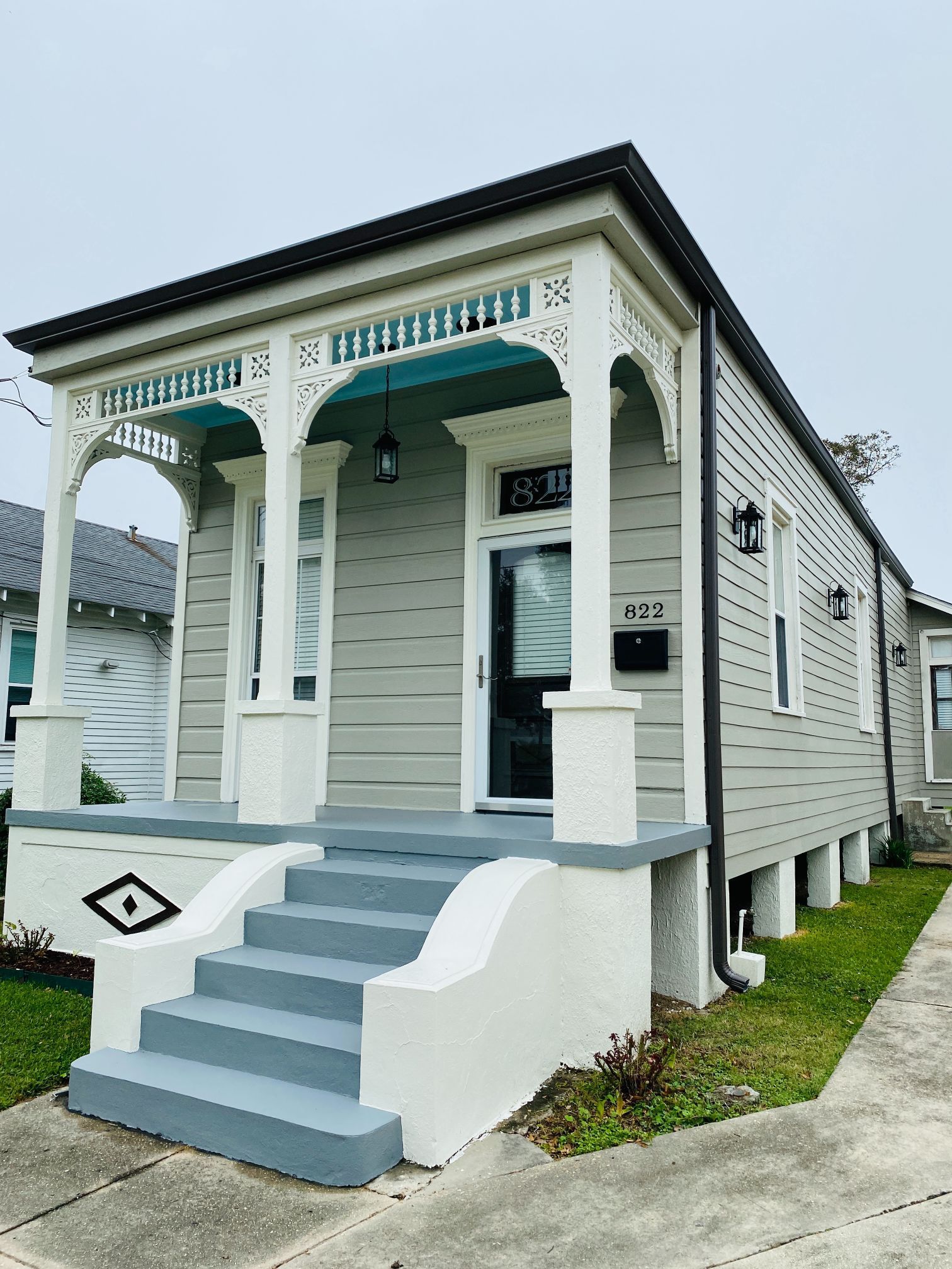 A small house with a porch and stairs in front of it.