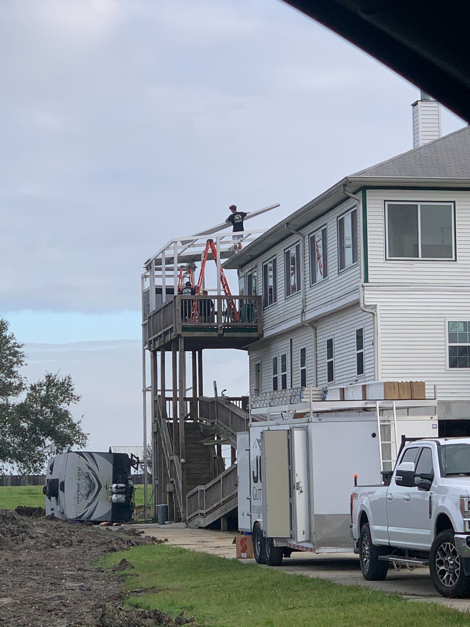 A large white house with a lot of windows and trucks parked in front of it