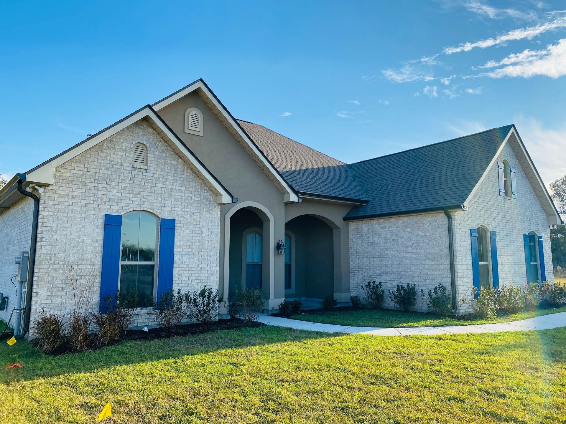 A white brick house with blue shutters and a black roof