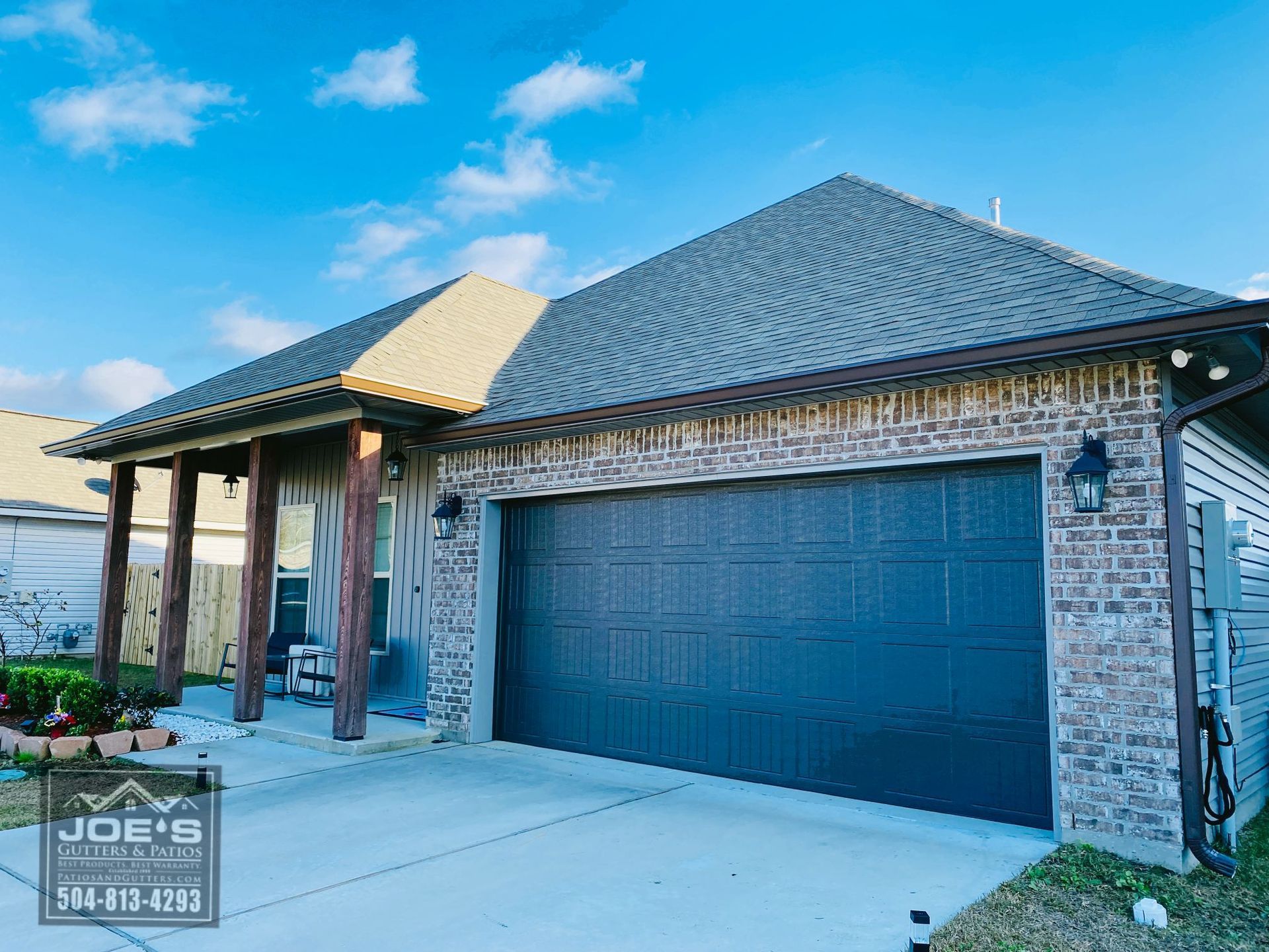 A brick house with a black garage door and a porch.