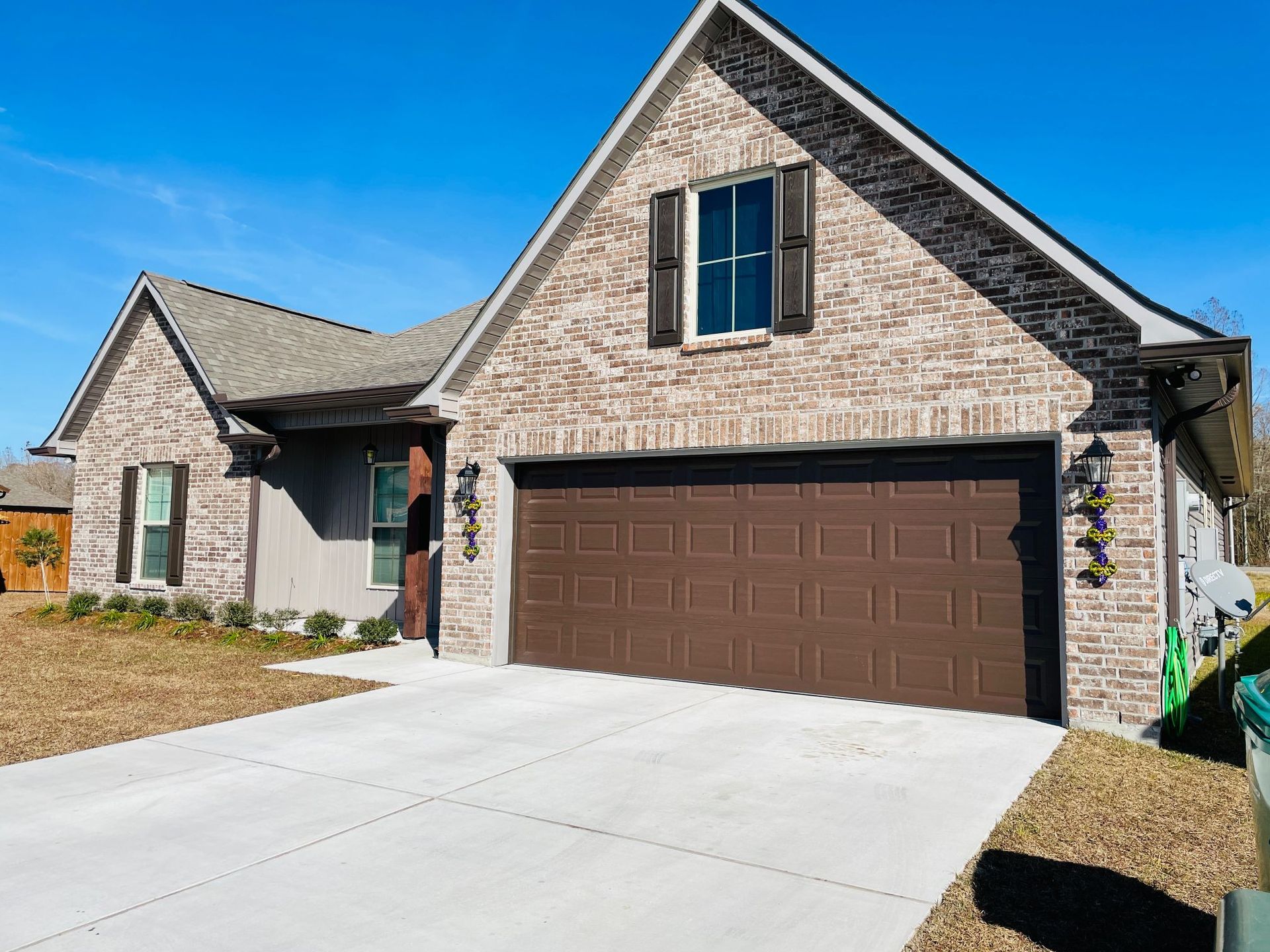 A brick house with a brown garage door and a concrete driveway.