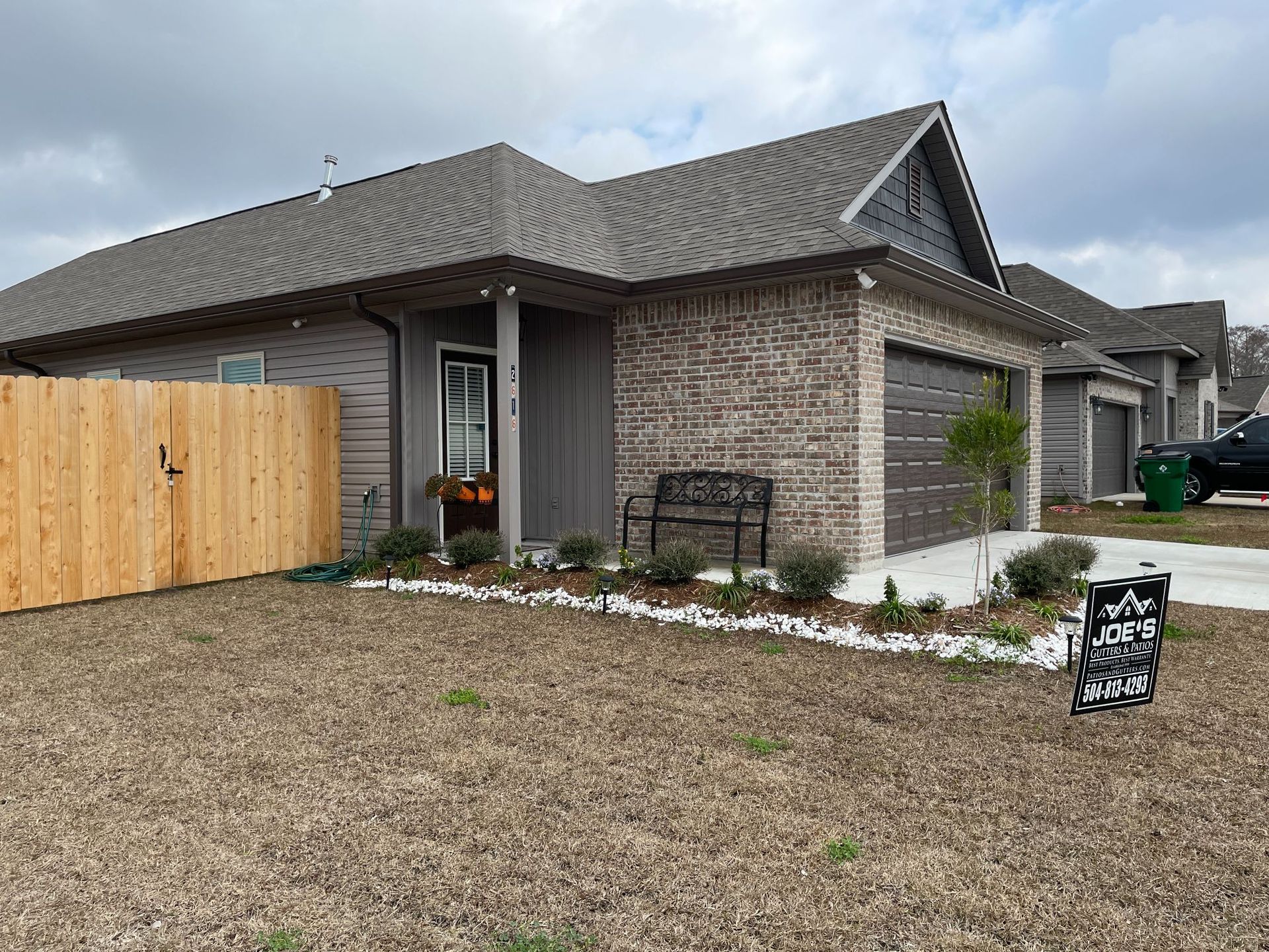 A house with a wooden fence and a bench in front of it.
