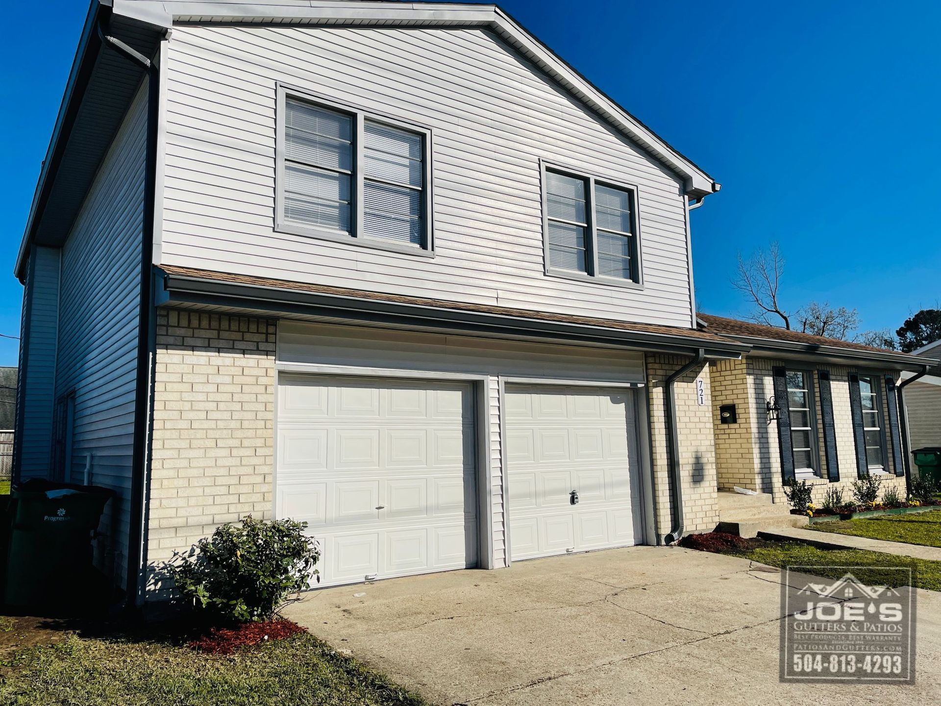 A white house with two garage doors is for sale