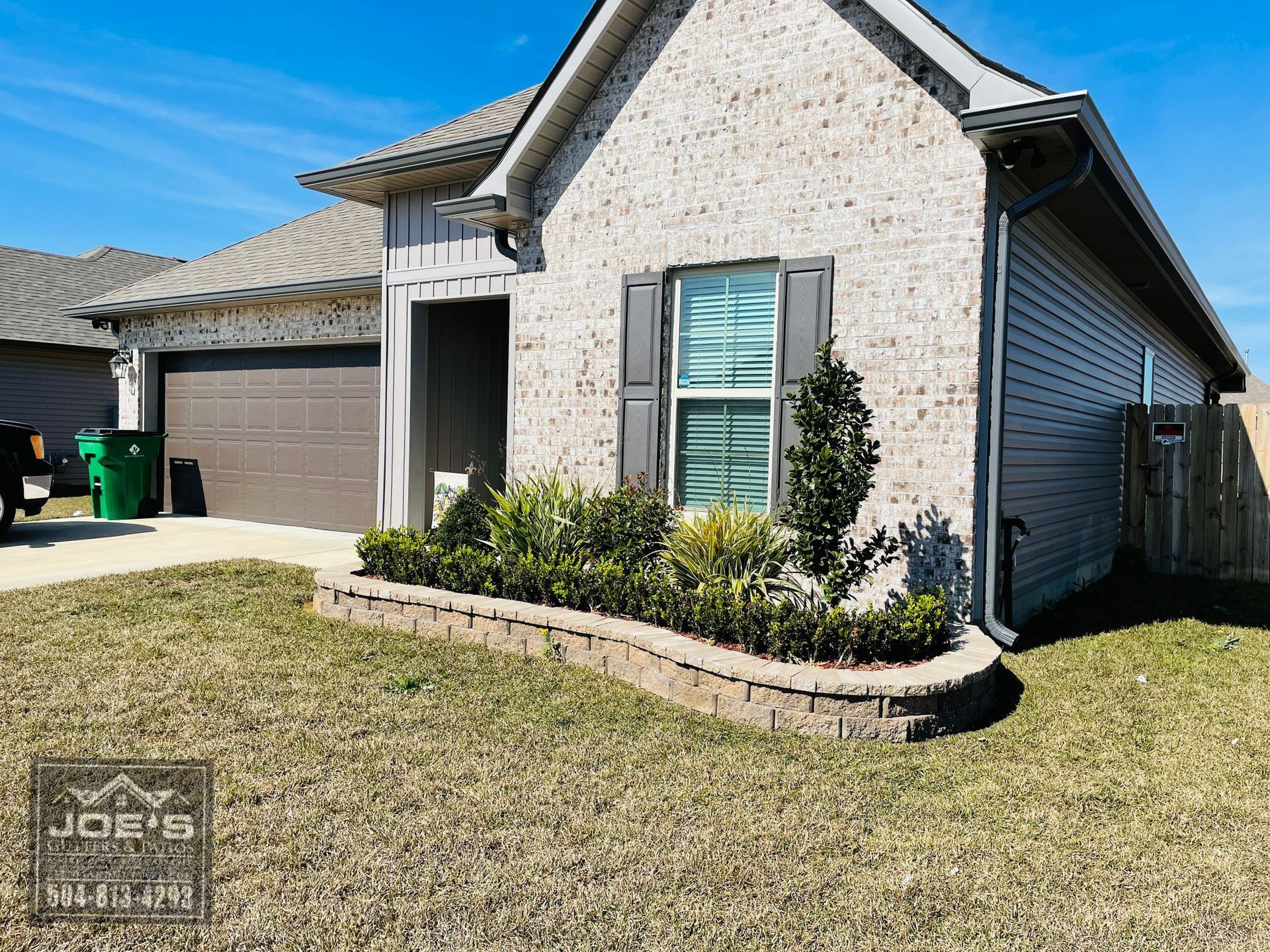A small brick house with a lush green lawn in front of it