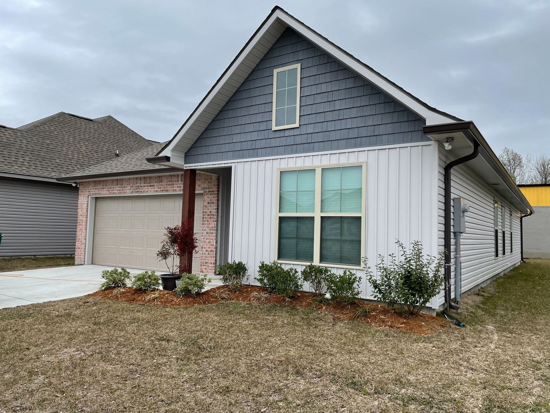 A small white house with a blue roof and a garage.