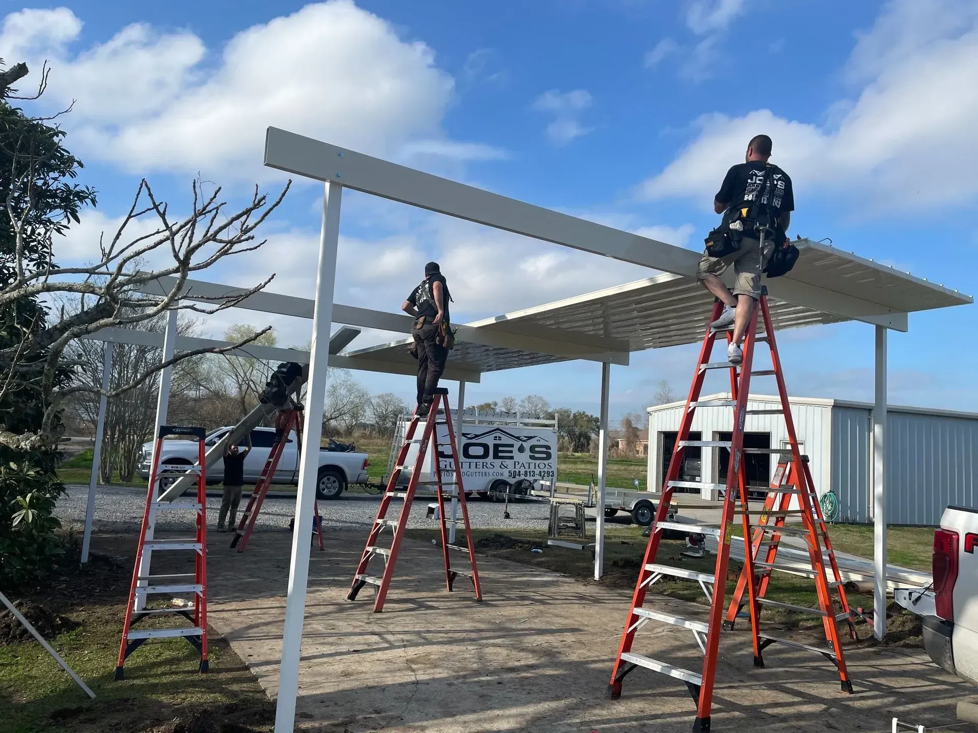 Workers on ladders installing a white canopy frame outdoors under a blue sky