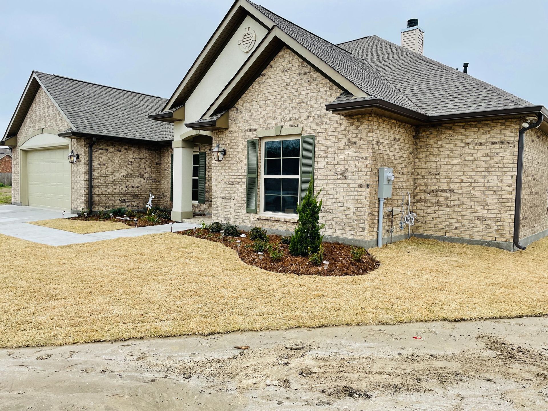 A large brick house with a gray roof and a large driveway.
