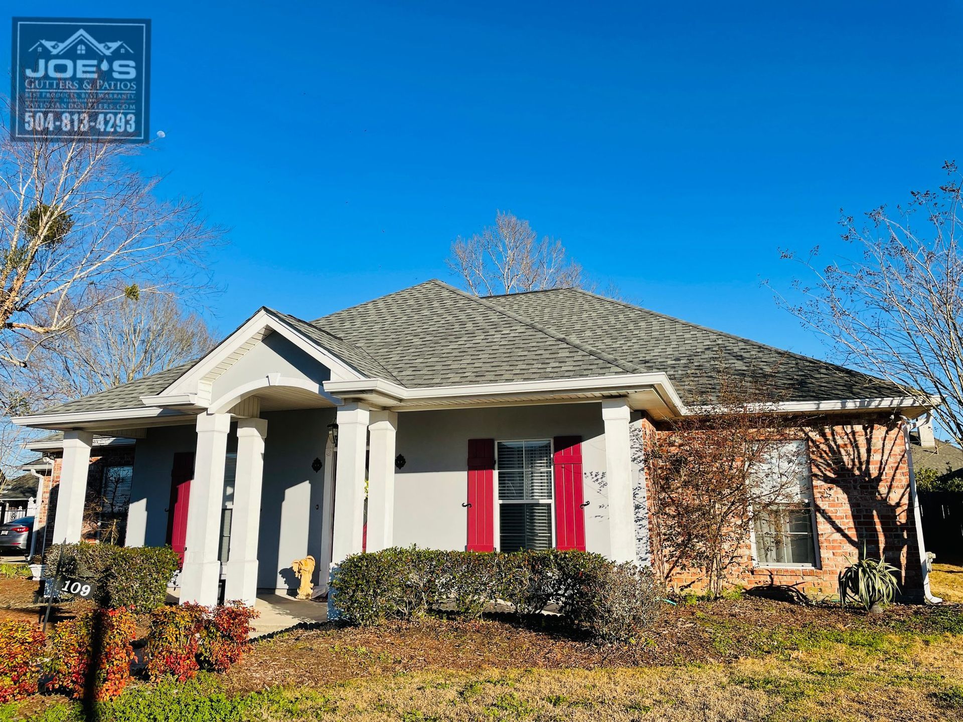 A house with a gray roof and red shutters is for sale.
