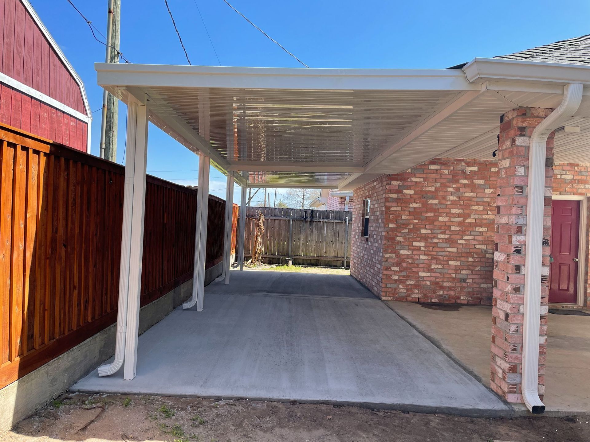 A carport is attached to the side of a brick house.