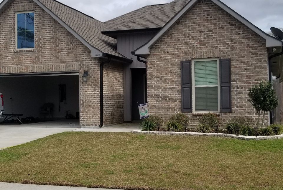 A large brick house with a garage and a car parked in front of it.