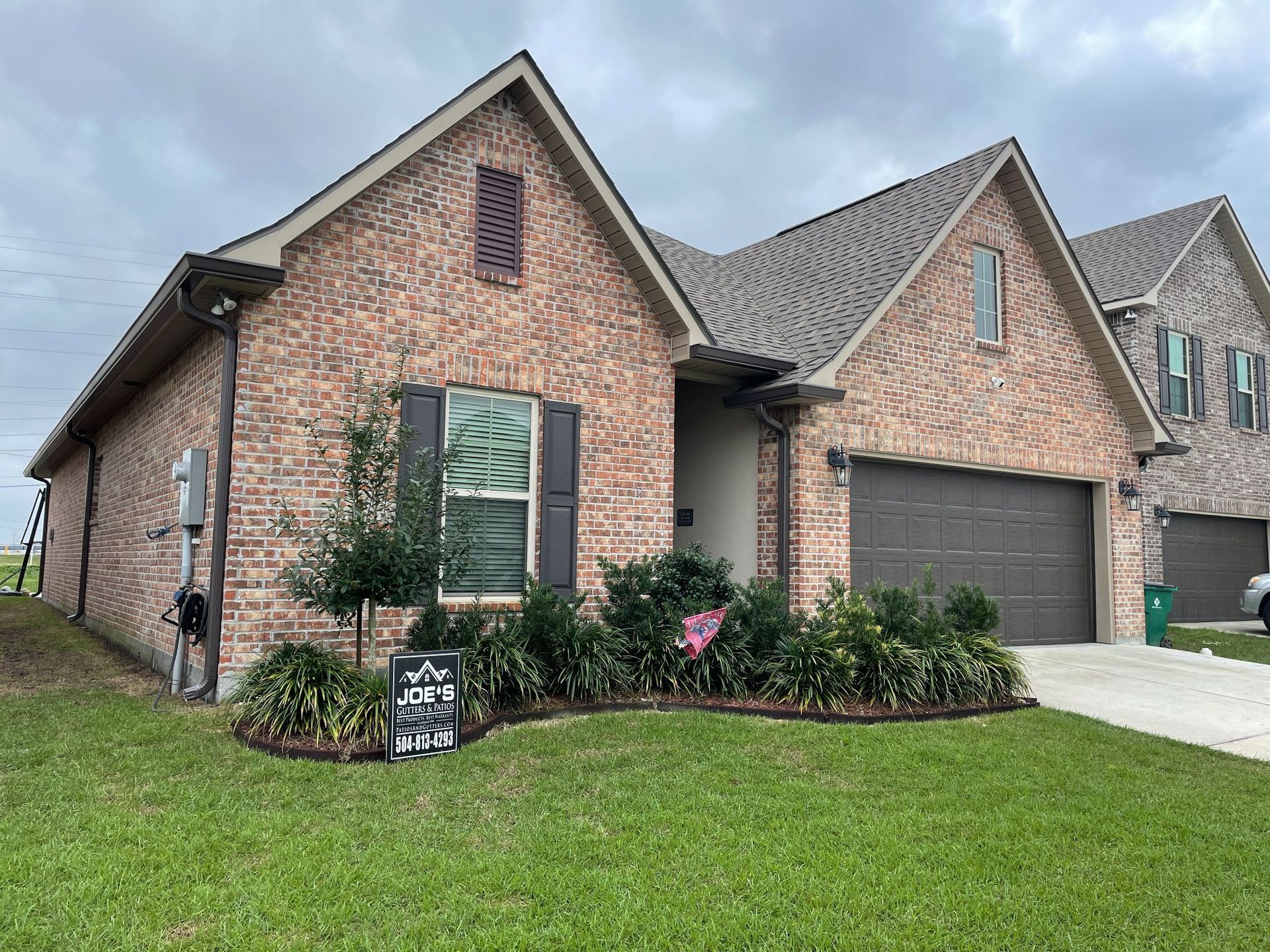 A brick house with a large garage and a sign in front of it.