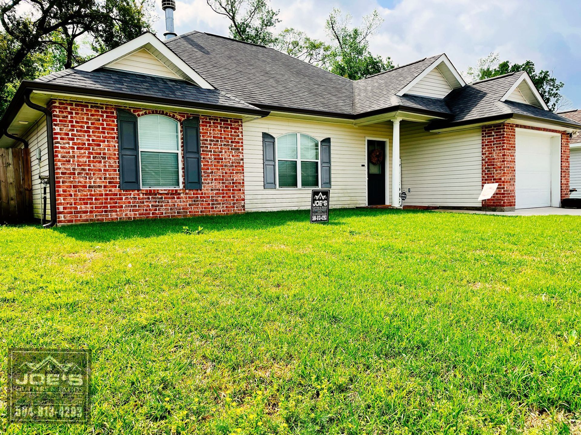 A brick house with a large lawn in front of it.