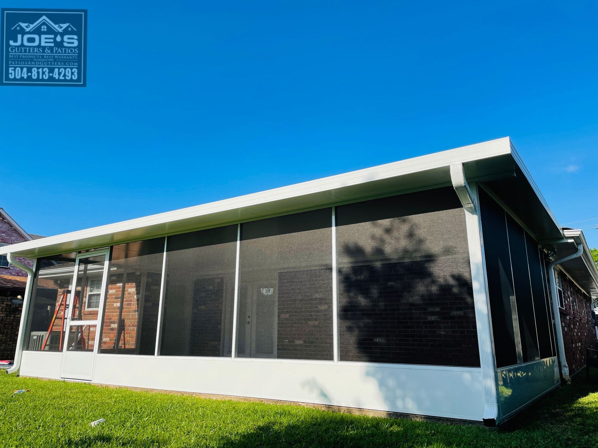 A house with a screened in porch and a blue sky in the background.