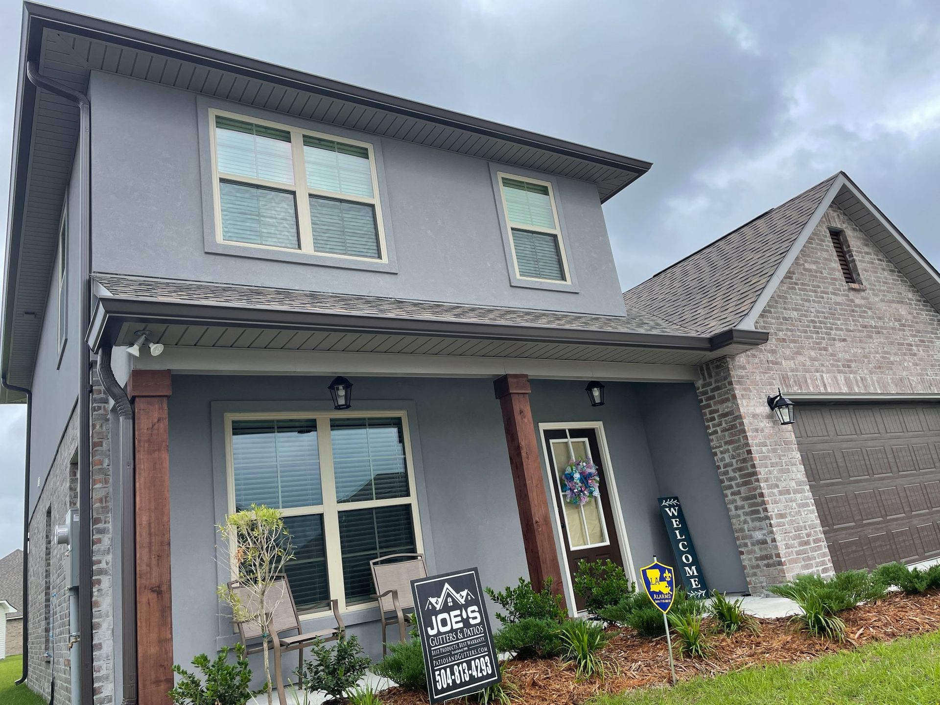 A gray house with a lot of windows and a sign in front of it.