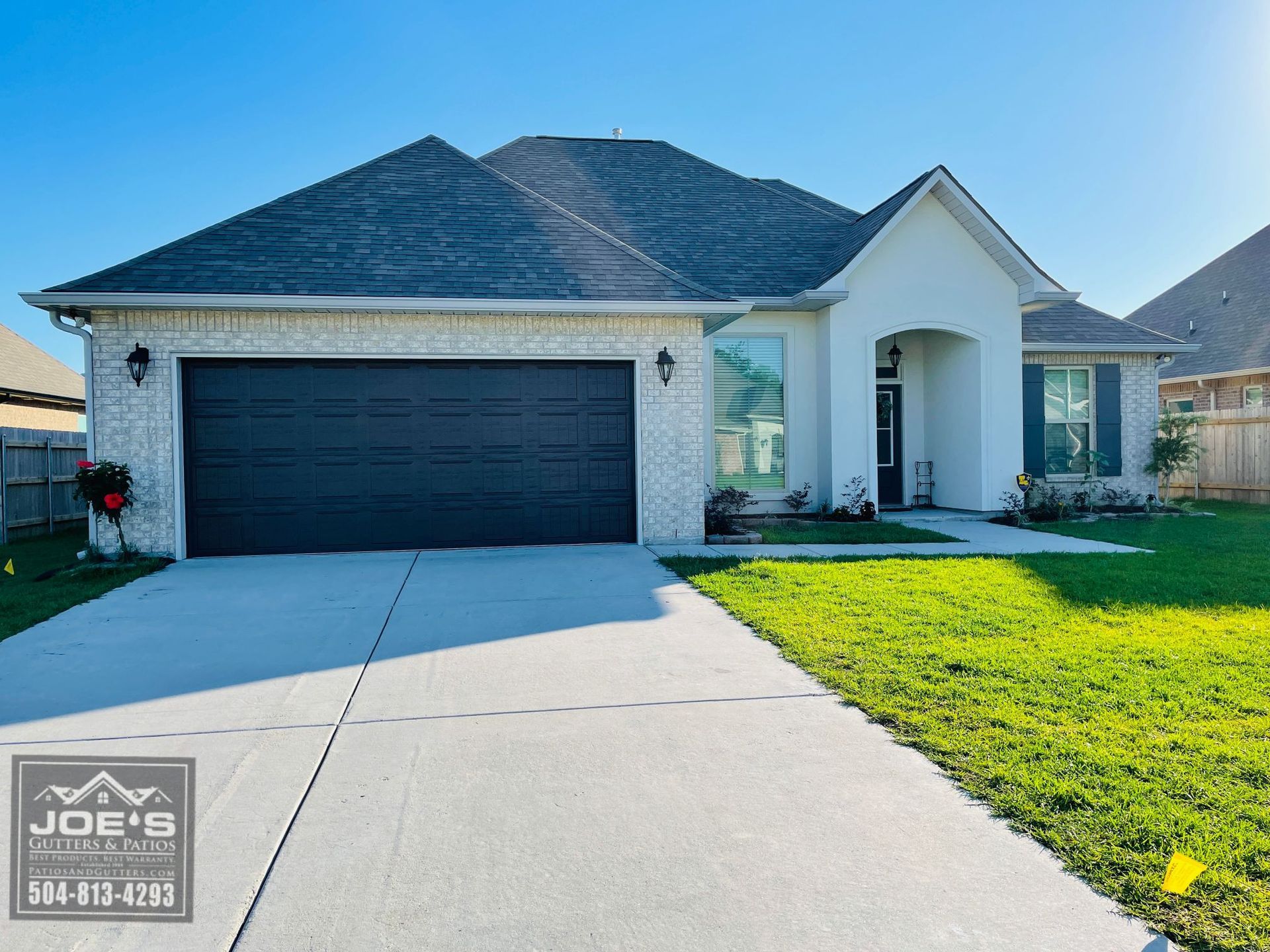 A white house with a black garage door is for sale