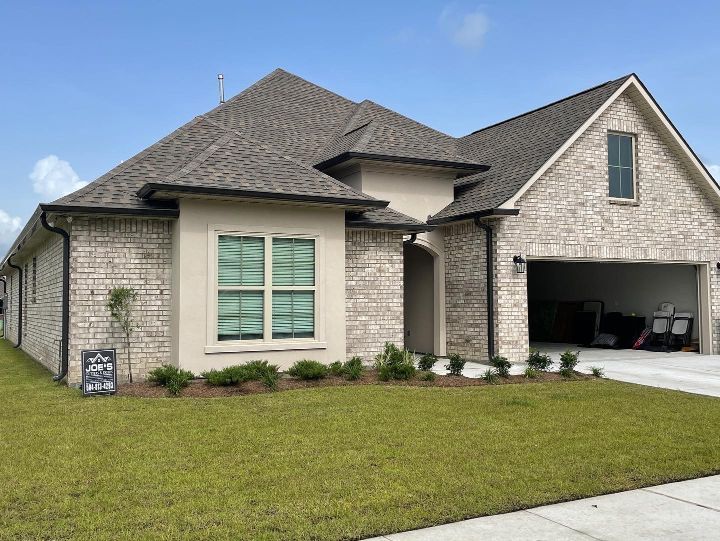 A large brick house with a garage and a sign in front of it.