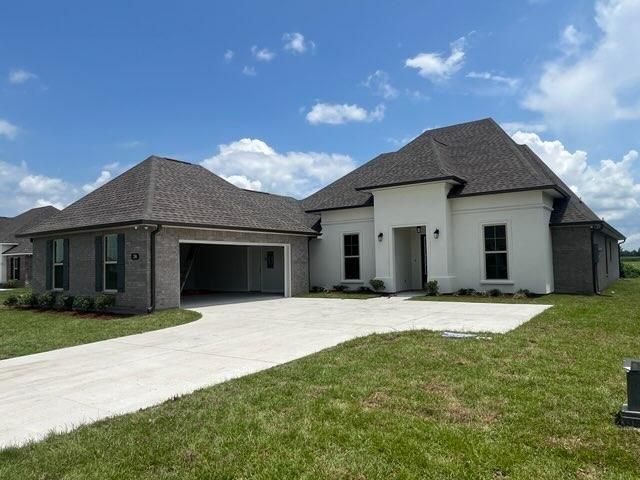Single-story house with a white stucco facade, brick siding, a two-car garage, and a large concrete driveway.