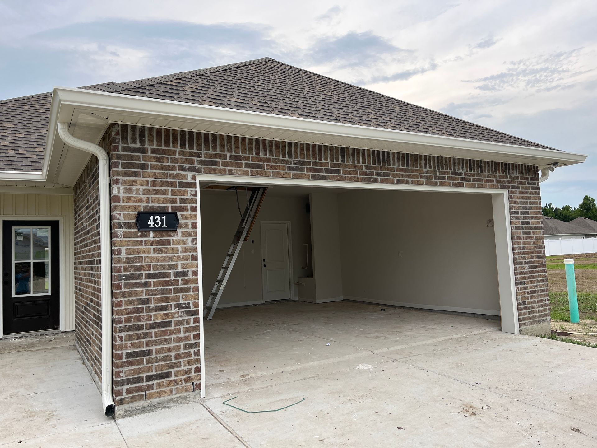 A newly constructed single-story brick home featuring an open garage, a white front door, and a brown shingle roof.