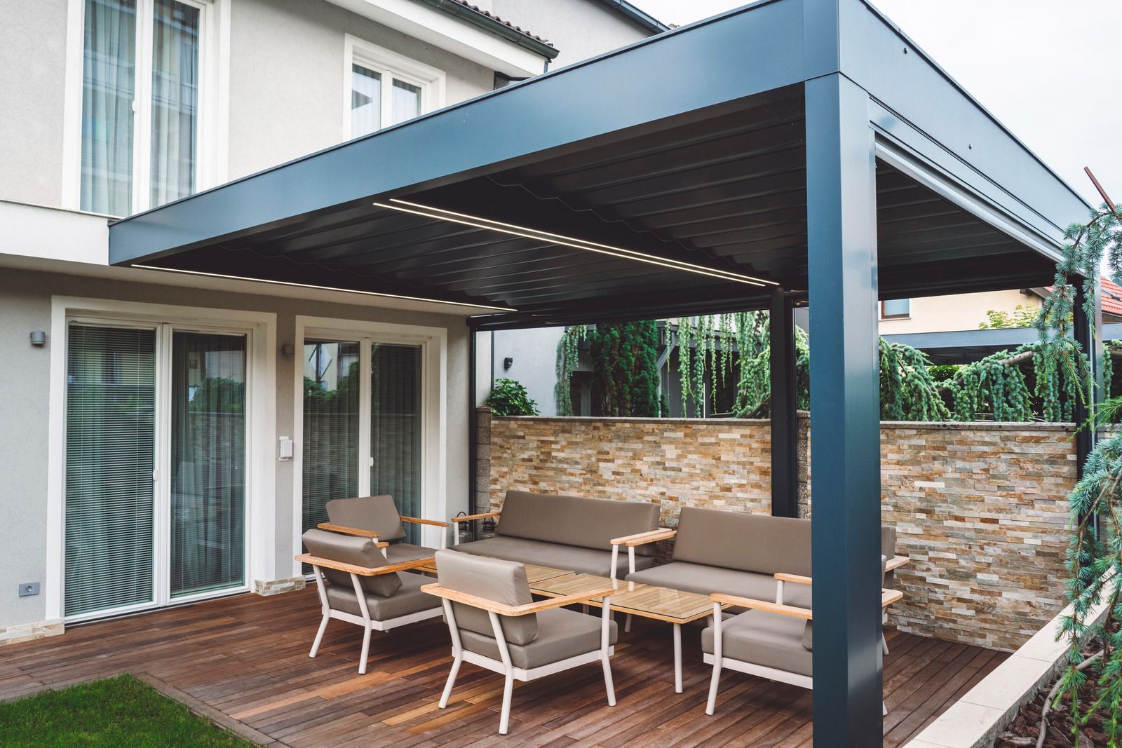 There is a pergola with a couch and chairs underneath it.