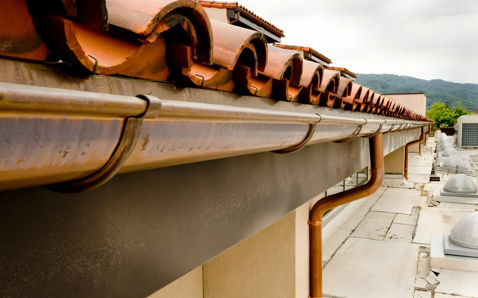 A close up of a gutter on a tiled roof