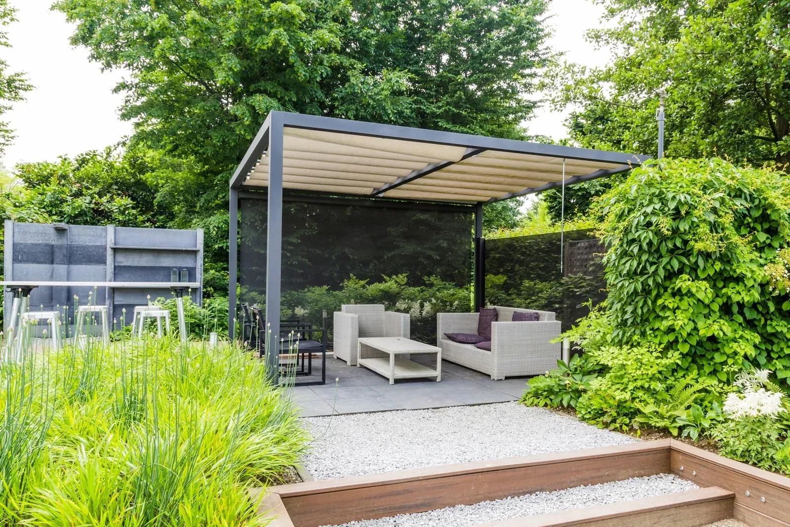 Outdoor patio with a pergola, seating, and greenery.