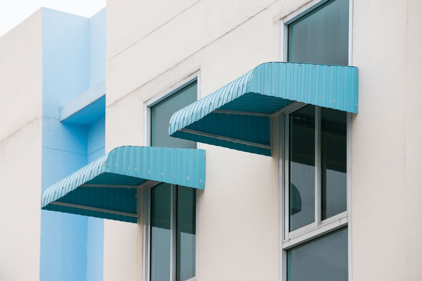 Blue awnings over windows on a white building facade