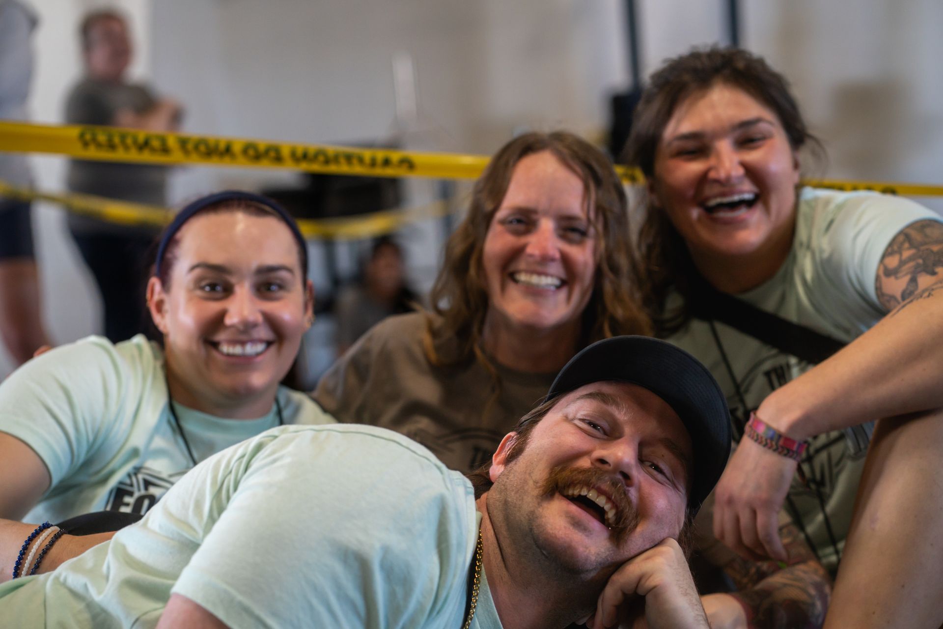Four smiling people pose close together indoors at CrossFit Common Fortitude, wearing light green shirts