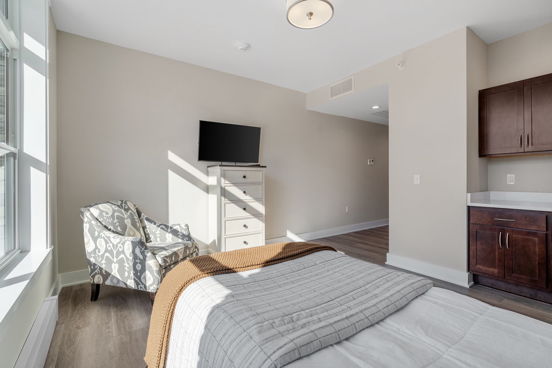 A bedroom with a bed , chair , television and cabinets.