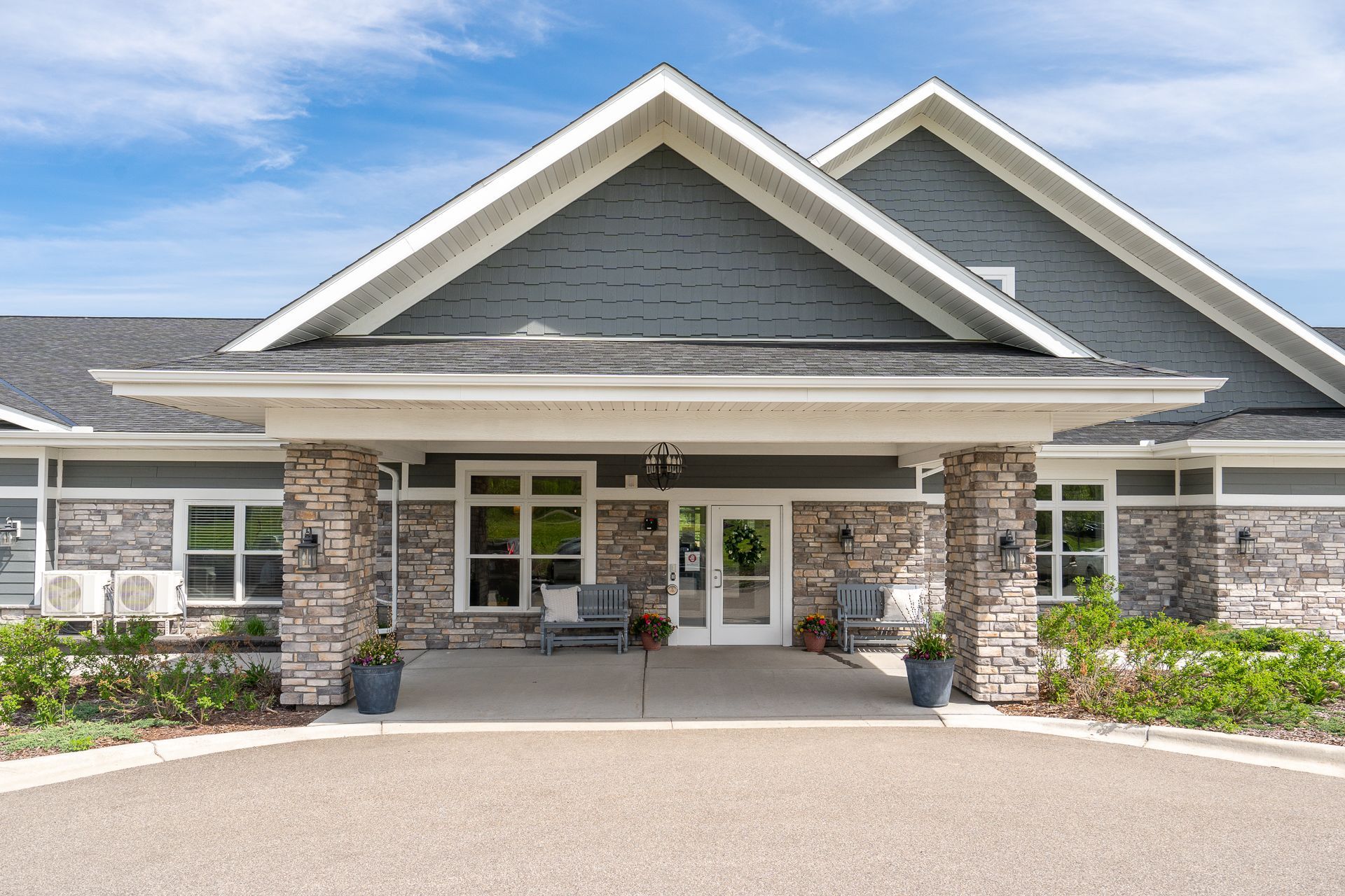 The front of a large house with a large porch and a driveway.