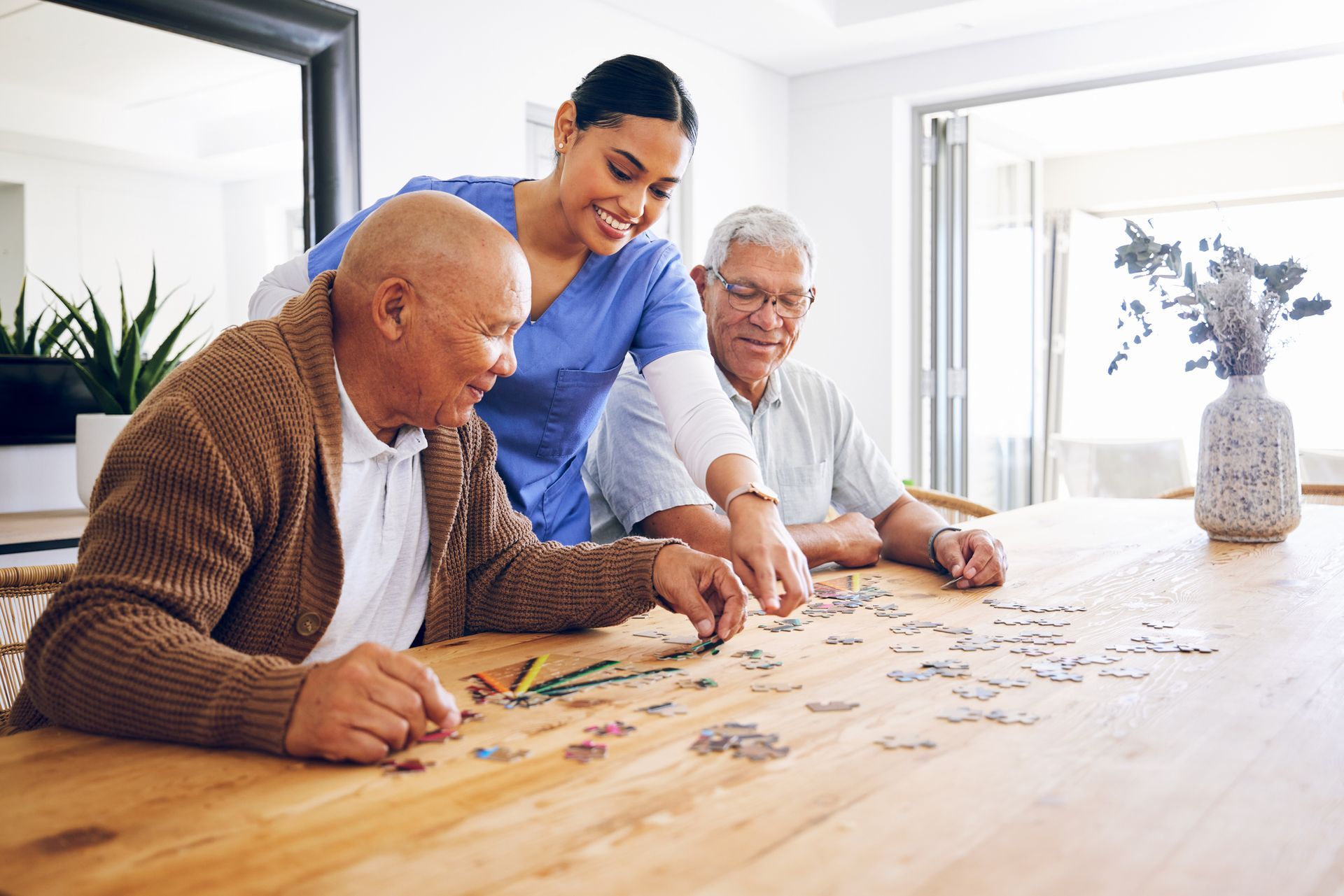 Elderly individuals work on a puzzle with caregiver at a bright, cozy senior living facility.