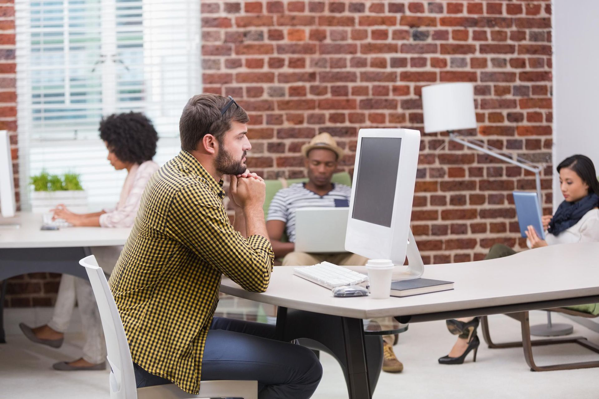 a man sits at a desk in front of a computer in an office