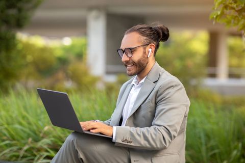 a man in a suit is using a laptop outside