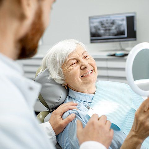 Old Woman Smiling in Mirror — Burleigh Denture Clinic in Burleigh Heads, QLD