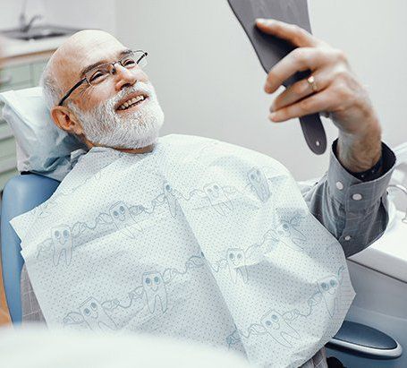 Old Man Looking at His Teeth on the Mirror — Burleigh Denture Clinic in Burleigh Heads, QLD