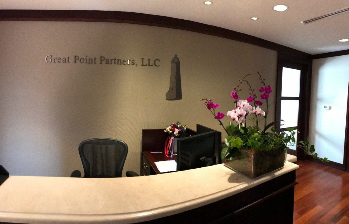 Modern reception desk with computer, flowers, and wall sign in an office lobby
