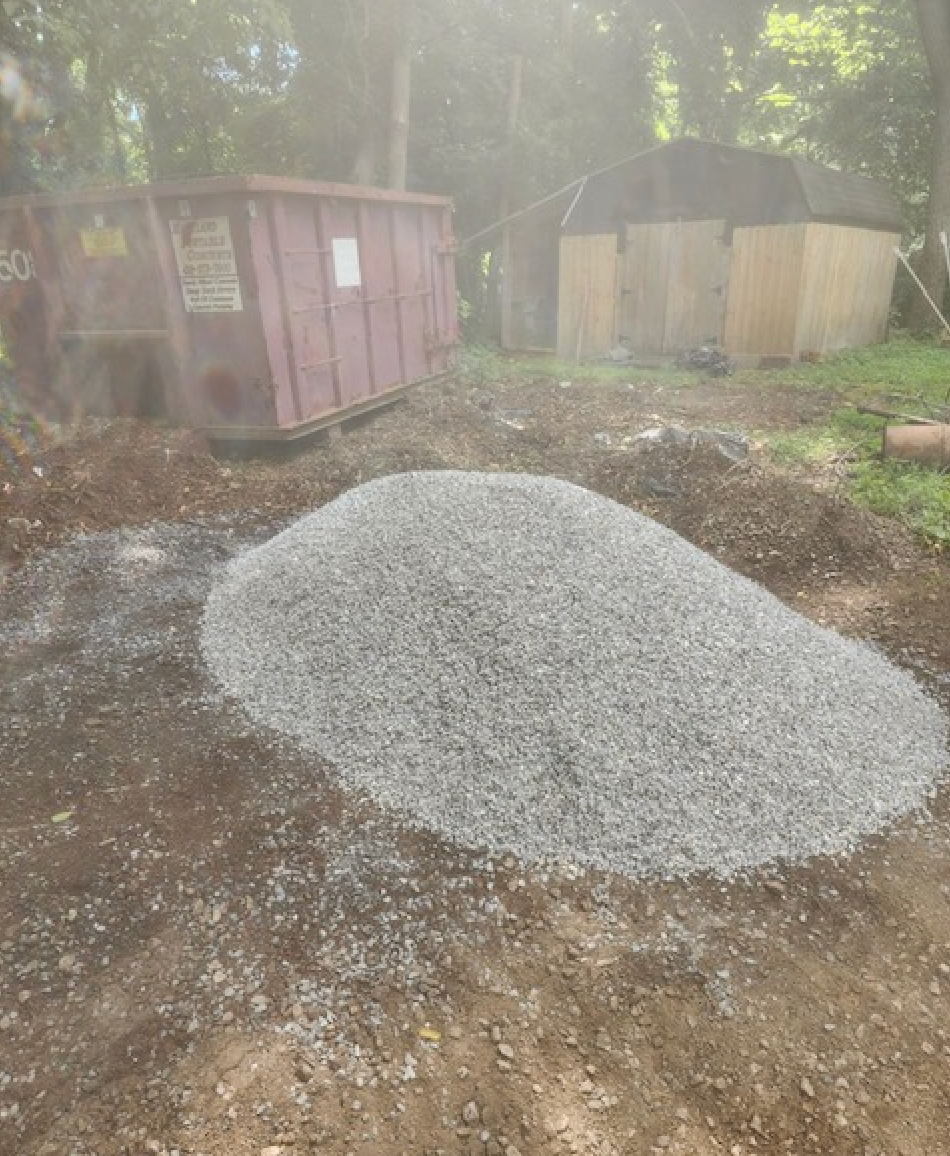 A pile of gravel is sitting in the middle of a dirt field.