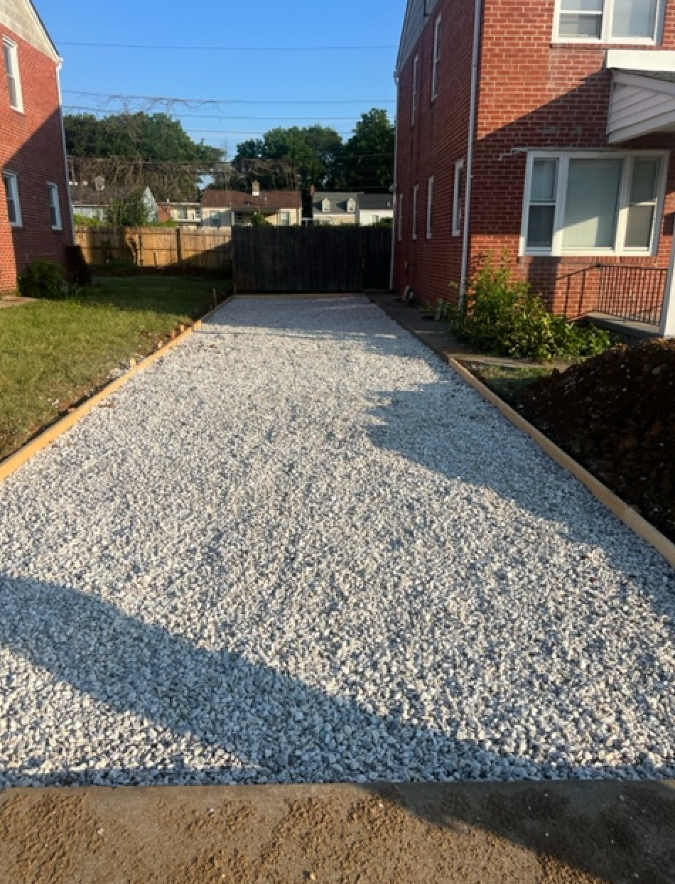 A gravel driveway in front of a brick house